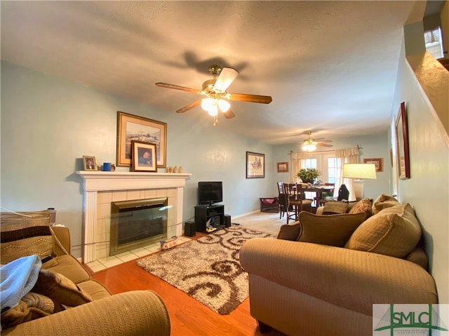 living room with ceiling fan, a fireplace, and light hardwood / wood-style flooring