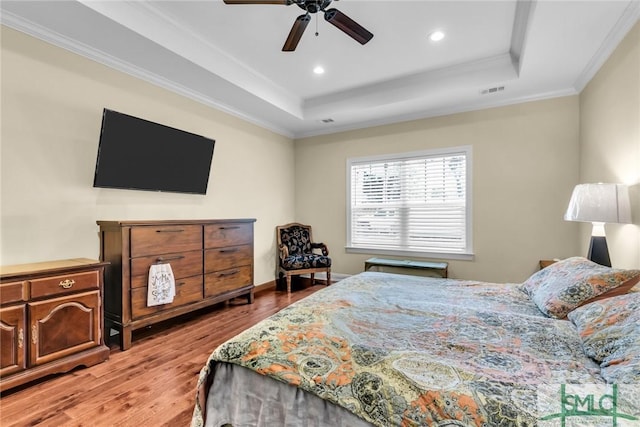 bedroom featuring crown molding, ceiling fan, a tray ceiling, and hardwood / wood-style flooring