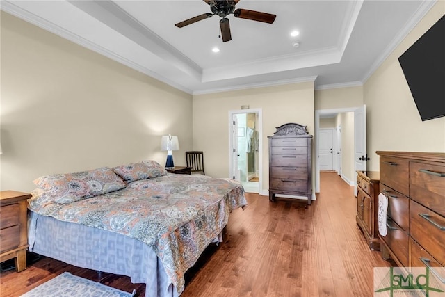 bedroom with wood-type flooring, crown molding, and a tray ceiling