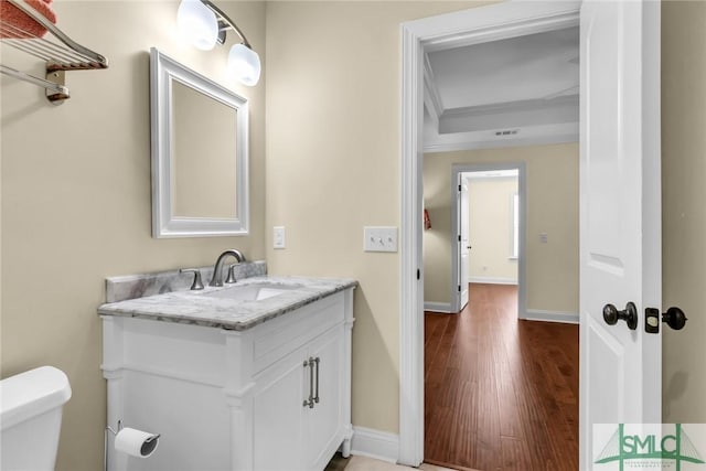 bathroom featuring vanity, ornamental molding, hardwood / wood-style floors, and toilet