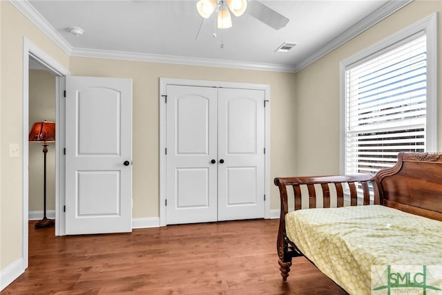 bedroom with hardwood / wood-style flooring, ornamental molding, ceiling fan, and a closet