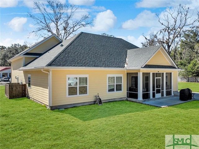 rear view of property featuring a lawn, a sunroom, and a patio area