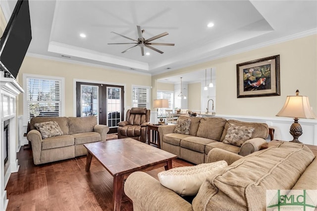 living room featuring french doors, a tray ceiling, dark hardwood / wood-style flooring, and crown molding