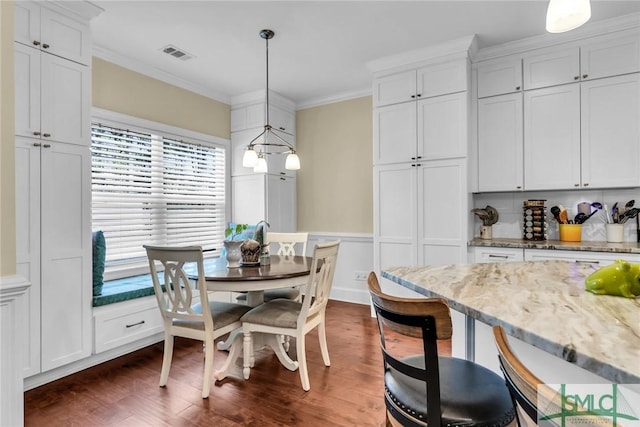 dining space featuring crown molding and dark wood-type flooring