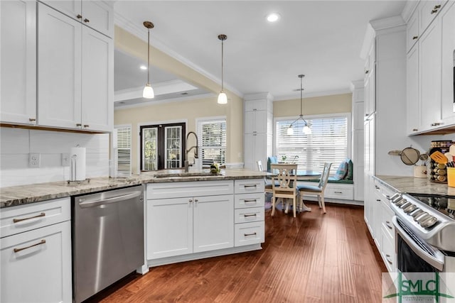 kitchen featuring sink, appliances with stainless steel finishes, white cabinetry, hanging light fixtures, and light stone countertops