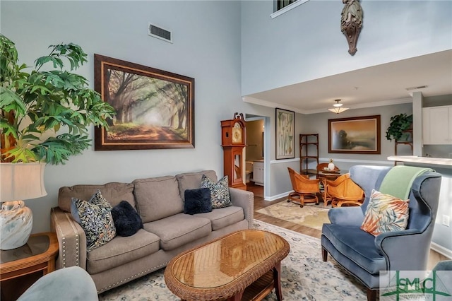 living room featuring a high ceiling, wood-type flooring, and crown molding