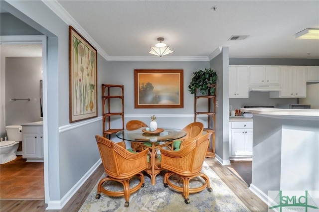 dining space featuring ornamental molding and wood-type flooring