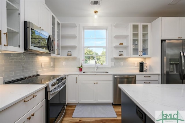 kitchen with white cabinetry, sink, backsplash, light stone counters, and stainless steel appliances