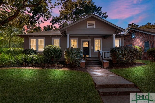 bungalow-style home featuring covered porch and a lawn