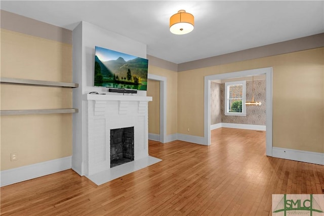 unfurnished living room featuring baseboards, a brick fireplace, and hardwood / wood-style flooring