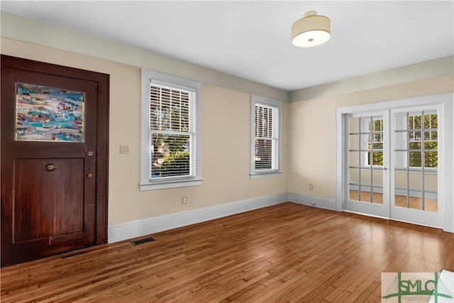 foyer entrance featuring hardwood / wood-style floors, visible vents, and baseboards