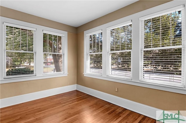 spare room with baseboards and wood finished floors