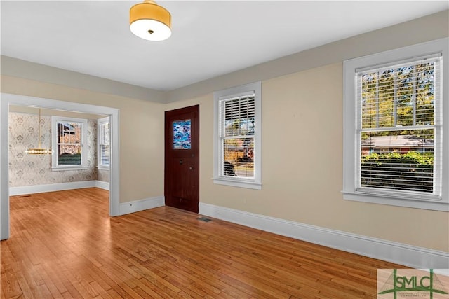 foyer featuring a healthy amount of sunlight, baseboards, and light wood finished floors