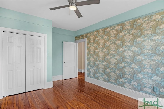 unfurnished bedroom featuring ceiling fan, a closet, baseboards, and wood finished floors