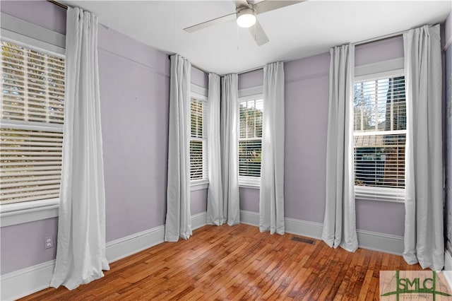 unfurnished room with visible vents, baseboards, ceiling fan, and hardwood / wood-style floors