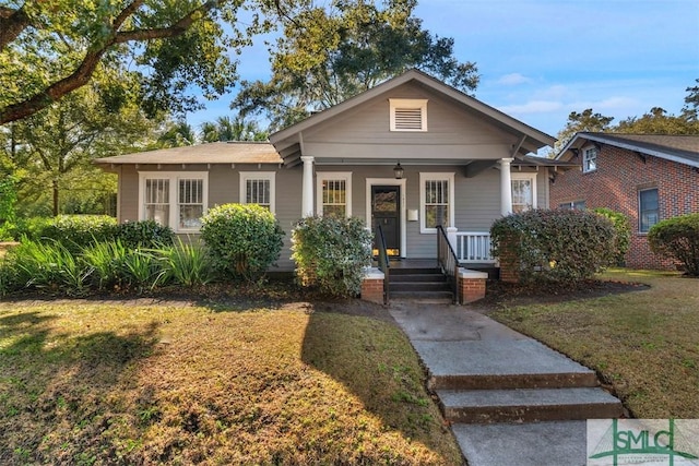 bungalow featuring covered porch and a front lawn