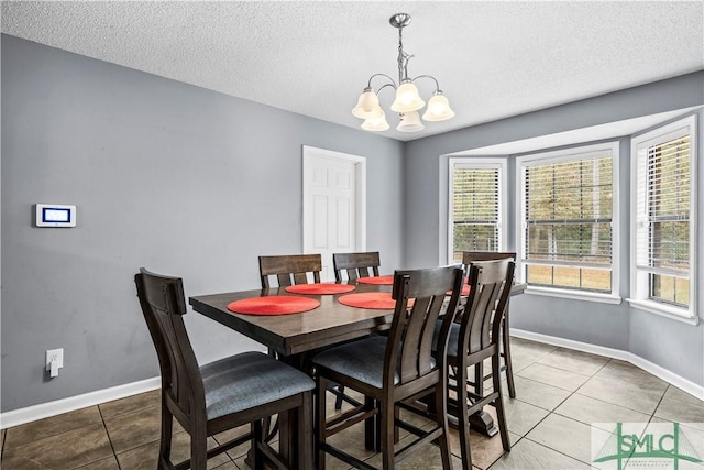 dining space with light tile patterned floors, a notable chandelier, a wealth of natural light, and a textured ceiling