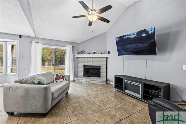 living room featuring tile patterned flooring, lofted ceiling, ceiling fan, and a brick fireplace