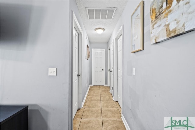 corridor with light tile patterned floors and a textured ceiling