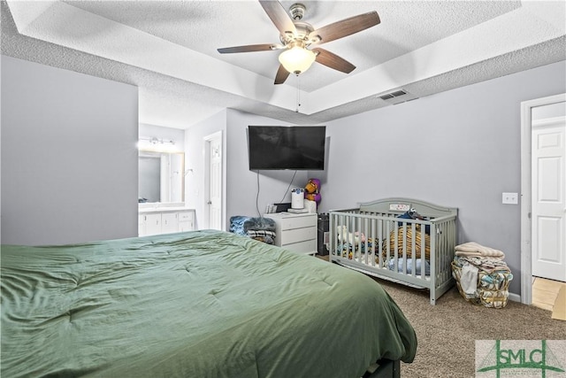 carpeted bedroom featuring ceiling fan, a tray ceiling, and a textured ceiling