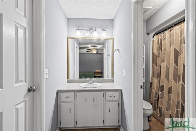 bathroom with vanity, ceiling fan, a textured ceiling, and toilet