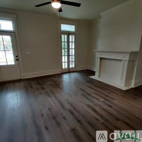 unfurnished living room with ornamental molding, dark hardwood / wood-style floors, ceiling fan, and french doors