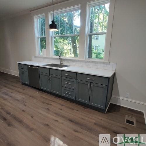 kitchen featuring stainless steel dishwasher, decorative light fixtures, sink, and gray cabinetry