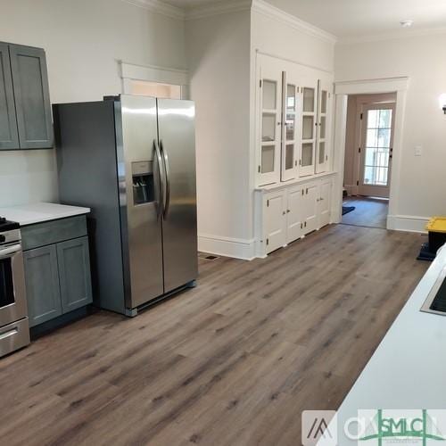 kitchen featuring crown molding, appliances with stainless steel finishes, gray cabinets, and wood-type flooring