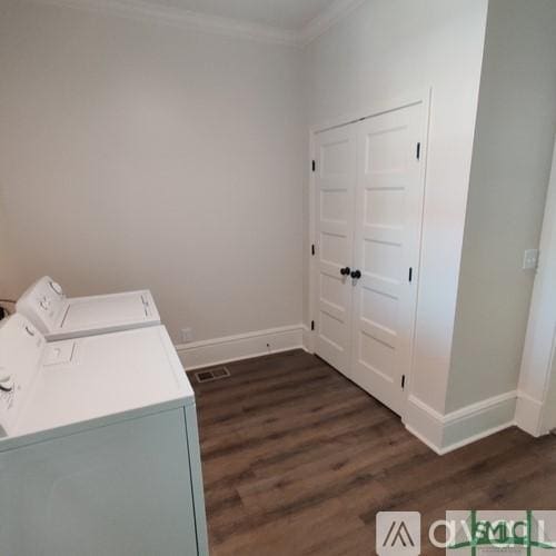 laundry room featuring ornamental molding, washing machine and clothes dryer, and dark hardwood / wood-style flooring