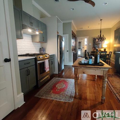 kitchen featuring stainless steel appliances, ornamental molding, hanging light fixtures, and dark hardwood / wood-style floors