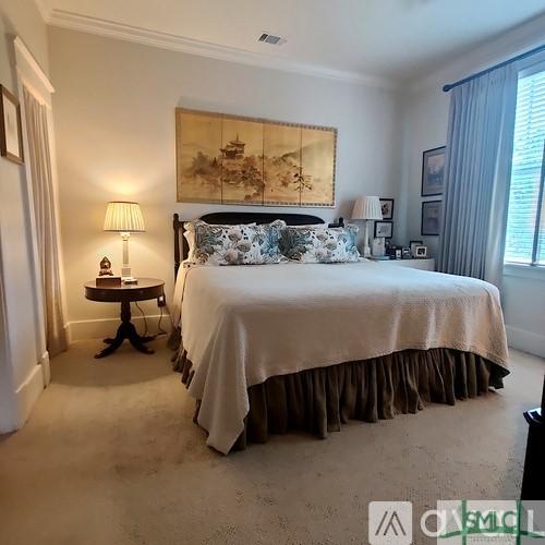 bedroom with crown molding and light colored carpet