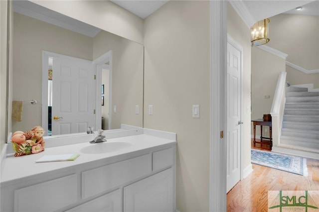 bathroom with vanity, hardwood / wood-style floors, crown molding, and a notable chandelier