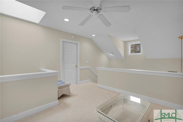 corridor with carpet floors and vaulted ceiling with skylight