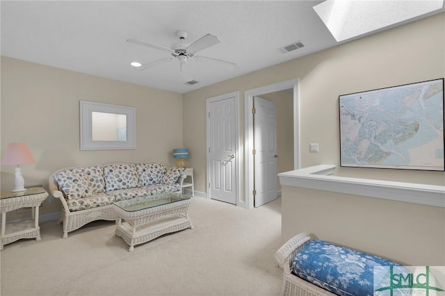 living room with light carpet, ceiling fan, and a skylight