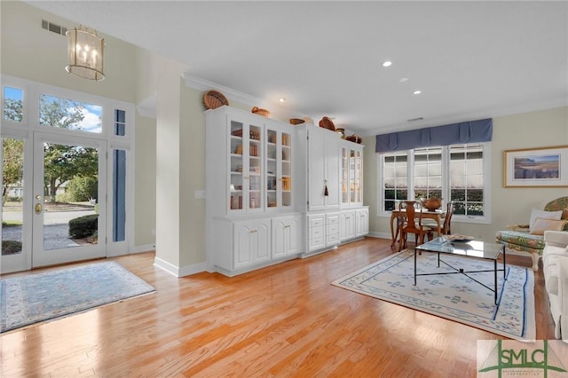 living room with ornamental molding, light hardwood / wood-style floors, and a wealth of natural light