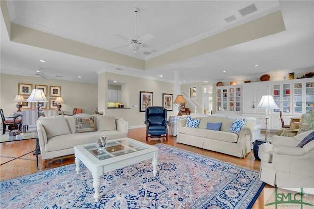 living room featuring crown molding, ceiling fan, and a raised ceiling