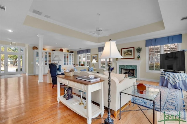 living room with a fireplace, a raised ceiling, and decorative columns