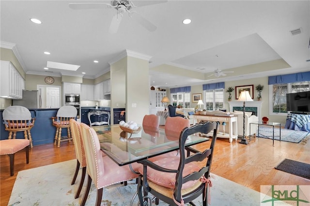 dining room featuring crown molding, a skylight, and light wood-type flooring