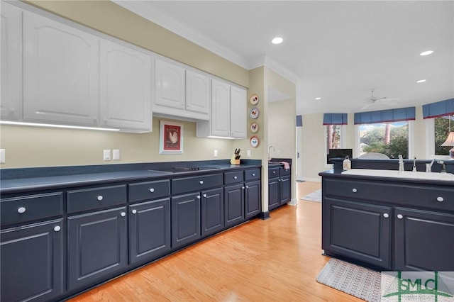 kitchen featuring crown molding, blue cabinetry, white cabinetry, black electric stovetop, and light hardwood / wood-style floors