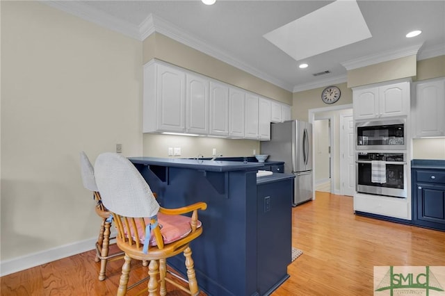 kitchen with appliances with stainless steel finishes, white cabinets, and a skylight