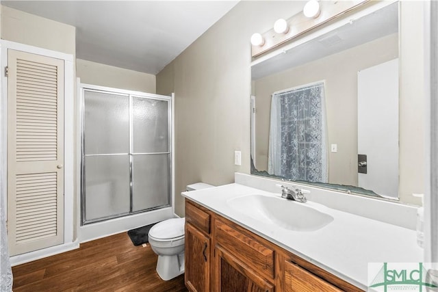 bathroom featuring vanity, wood-type flooring, toilet, and walk in shower