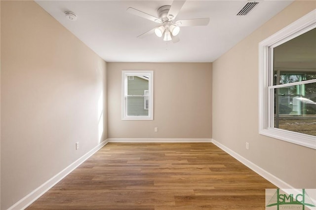 empty room featuring a healthy amount of sunlight, hardwood / wood-style floors, and ceiling fan