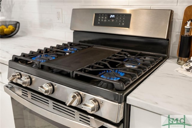 details featuring tasteful backsplash, gas stove, and light stone counters