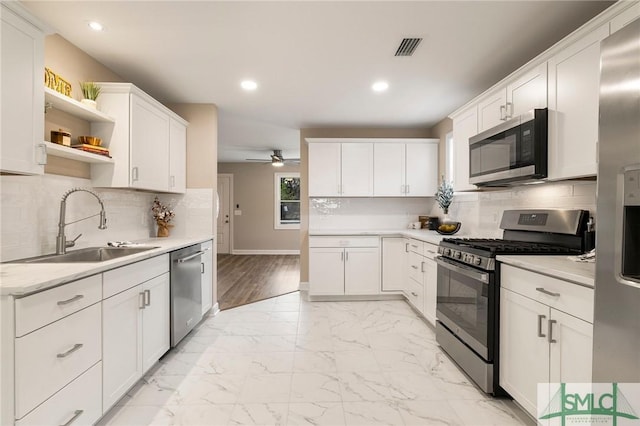 kitchen with sink, white cabinets, ceiling fan, stainless steel appliances, and backsplash