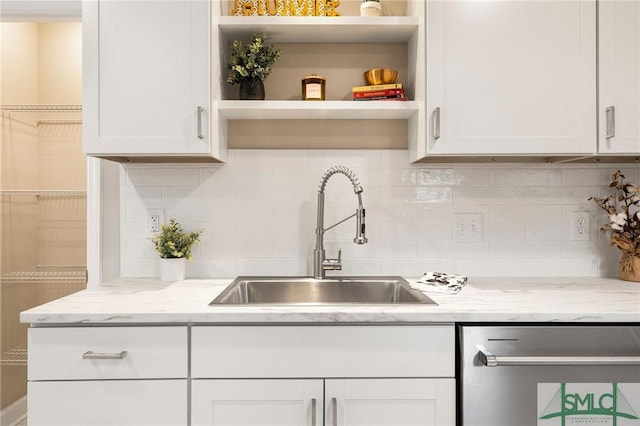 kitchen featuring white cabinetry, sink, light stone counters, and decorative backsplash