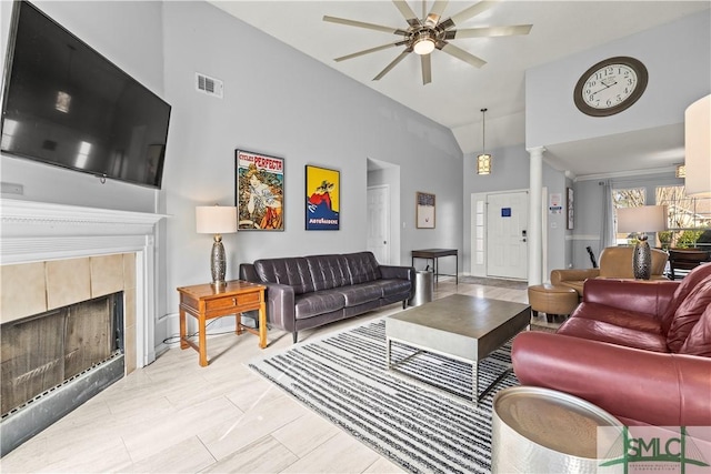 living room featuring decorative columns, a tile fireplace, high vaulted ceiling, and ceiling fan