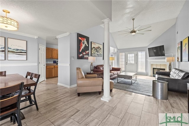 living room featuring ceiling fan, decorative columns, a textured ceiling, a tiled fireplace, and vaulted ceiling