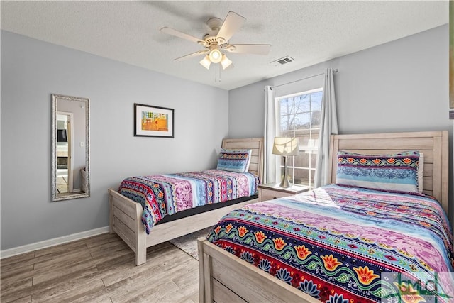 bedroom featuring ceiling fan, a textured ceiling, and light wood-type flooring