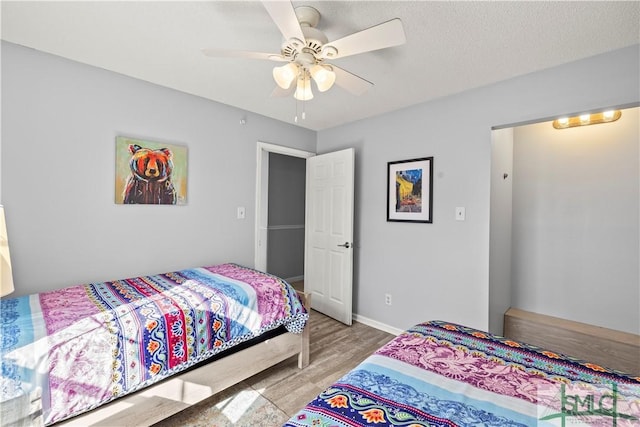 bedroom with ceiling fan, light hardwood / wood-style floors, and a textured ceiling