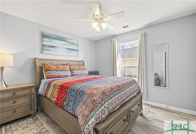 bedroom with ceiling fan, a textured ceiling, and light wood-type flooring